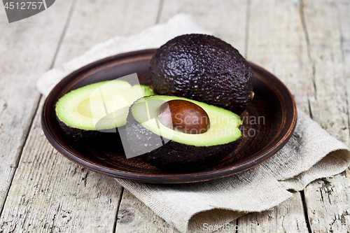 Image of Fresh organic avocado on ceramic plate and linen napkin on rusti