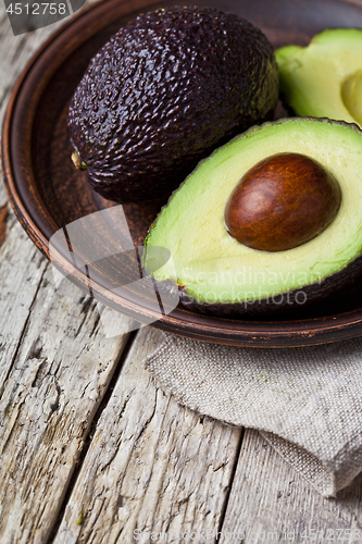 Image of Fresh organic avocado on ceramic plate and linen napkin on rusti