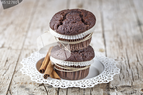 Image of Fresh dark chocolate muffins with cinnamon sticks on white plate