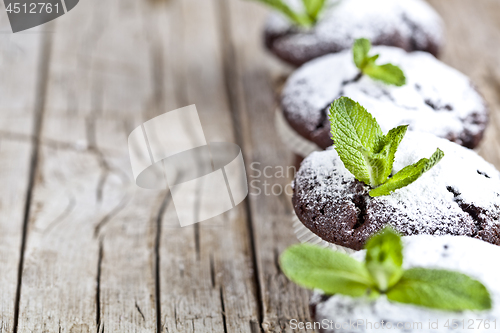 Image of Fresh chocolate dark muffins with sugar powder and mint leaf on 