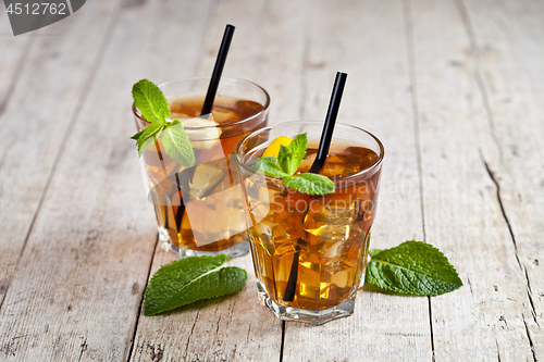 Image of Cold iced tea with lemon, mint leaves and ice cubes in two glass