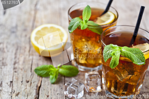 Image of Cold iced tea with lemon, mint leaves and ice cubes in two glass