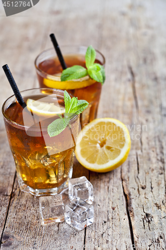 Image of Cold iced tea with lemon, mint leaves and ice cubes in two glass