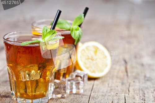 Image of Cold iced tea with lemon, mint leaves and ice cubes in two glass