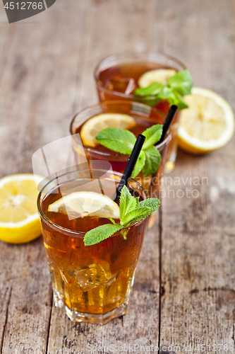 Image of Cold iced tea with lemon, mint leaves and ice cubes in three gla