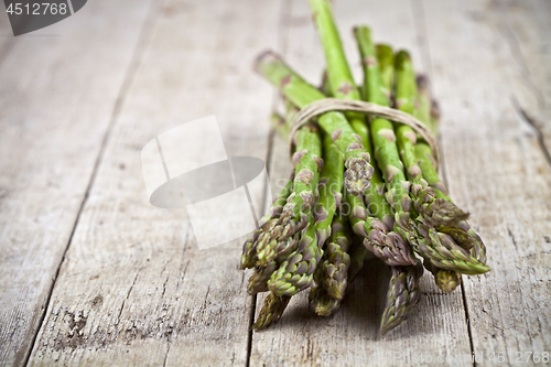 Image of Bunch of fresh raw garden asparagus on rustic wooden table backg