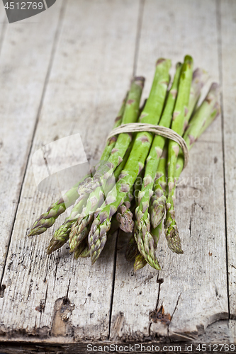 Image of Bunch of fresh raw garden asparagus on rustic wooden table backg