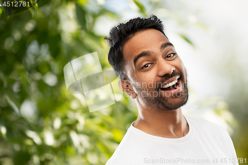 Image of laughing indian man over green natural background
