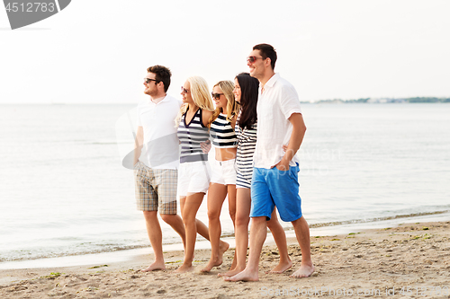 Image of friends in striped clothes walking along beach