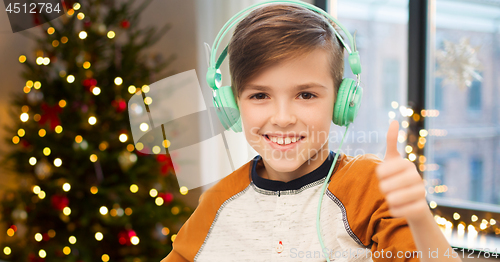 Image of boy in earphones showing thumbs up on christmas