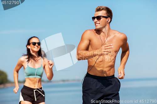 Image of couple with earphones running along on beach