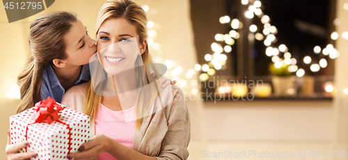 Image of daughter and mother with christmas gift at home