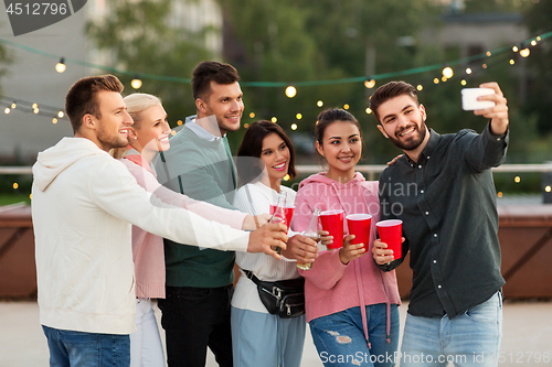 Image of friends with drinks taking selfie at rooftop party