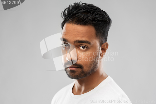 Image of serious young indian man over gray background