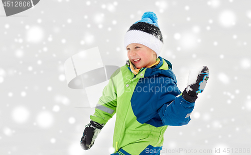 Image of happy boy playing and throwing snowball in winter