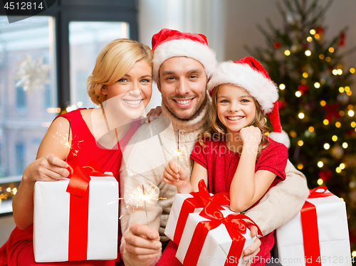 Image of family with christmas gifts and sparklers at home