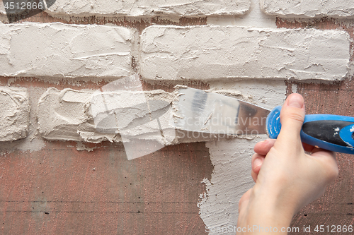 Image of Plasterer manually works with a spatula and smooths the plaster on the wall