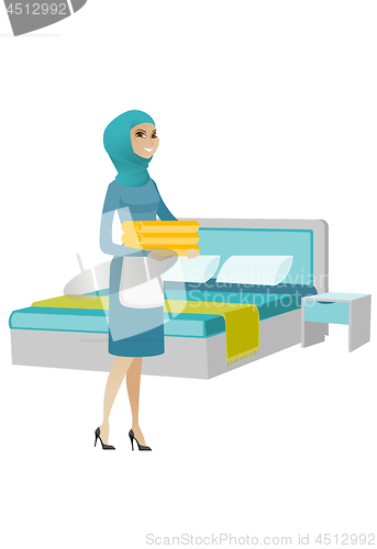 Image of Muslim housekeeping maid with stack of linen.