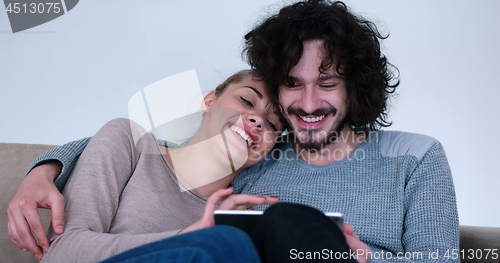 Image of couple relaxing at  home with tablet computers