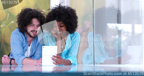 Image of Couple relaxing together at home with tablet computer