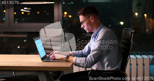 Image of man working on laptop in dark office