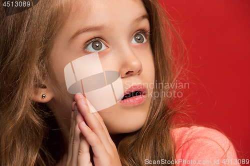 Image of Beautiful teen girl looking suprised isolated on red