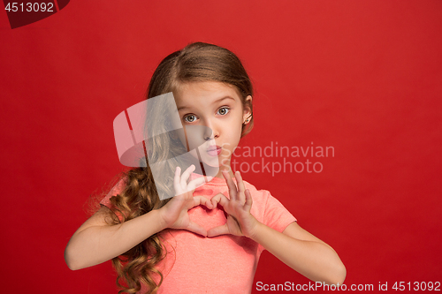 Image of The happy teen girl standing and smiling against red background.