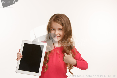 Image of Little funny girl with tablet on green background