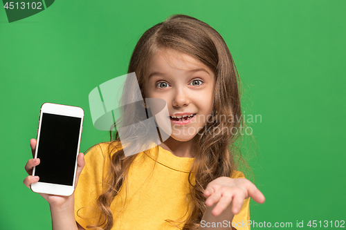 Image of The happy teen girl standing and smiling against green background.