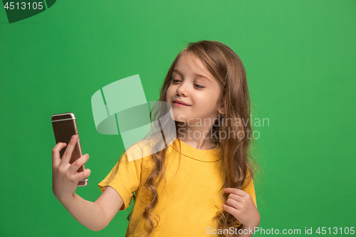 Image of The happy teen girl standing and smiling against green background.