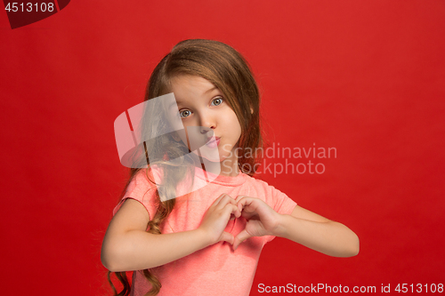 Image of The happy teen girl standing and smiling against red background.