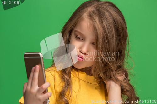 Image of The happy teen girl standing and smiling against green background.