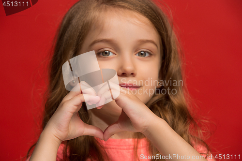 Image of The happy teen girl standing and smiling against red background.