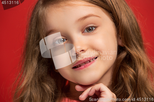 Image of The happy teen girl standing and smiling against red background.