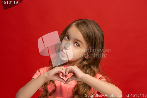Image of The happy teen girl standing and smiling against red background.