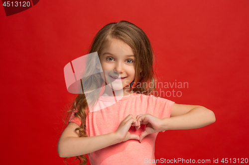 Image of The happy teen girl standing and smiling against red background.