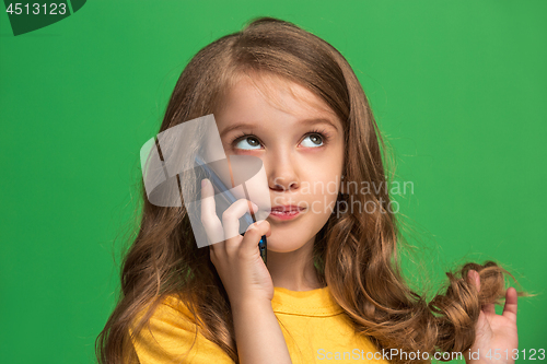 Image of The happy teen girl standing and smiling against green background.