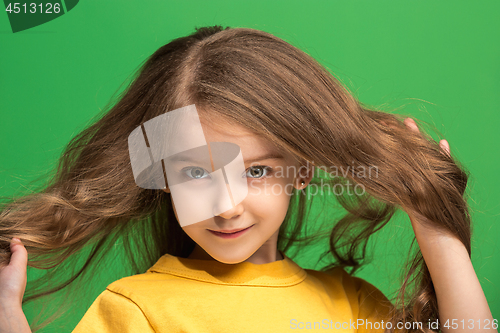 Image of The happy teen girl standing and smiling against green background.
