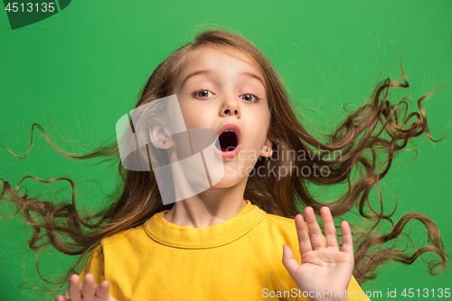 Image of Beautiful teen girl looking suprised isolated on green