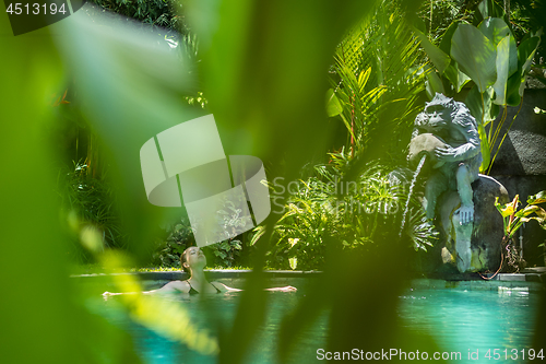 Image of Sensual young woman relaxing in outdoor spa infinity swimming pool surrounded with lush tropical greenery of Ubud, Bali.