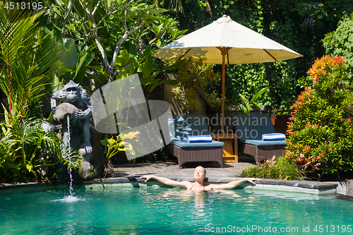 Image of Sensual young woman relaxing in outdoor spa infinity swimming pool surrounded with lush tropical greenery of Ubud, Bali.