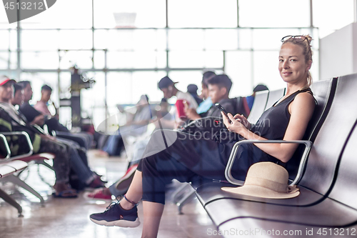 Image of Female traveler using her cell phone while waiting to board a plane at departure gates at asian airport terminal.