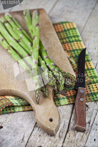 Image of Raw garden asparagus and knife closeup on cutting board on rusti