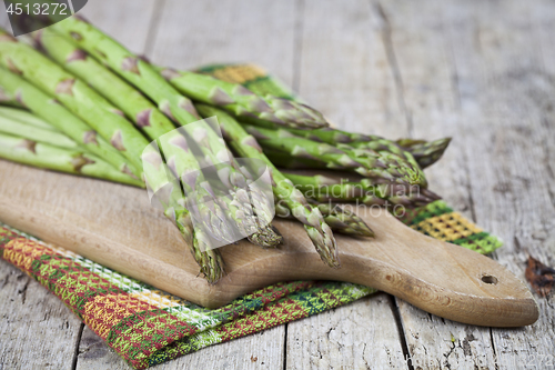 Image of Organic raw garden asparagus on cutting board on rustic wooden t