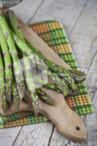 Image of Organic raw garden asparagus on cutting board on rustic wooden t