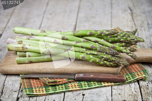 Image of Organic raw garden asparagus and knife closeup on cutting board 