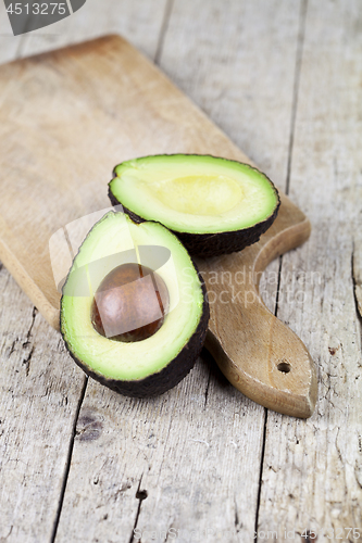 Image of Fresh organic avocado halves on cutting board on old wooden tabl