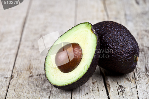 Image of Fresh organic avocado halves on old wooden table background. Fre