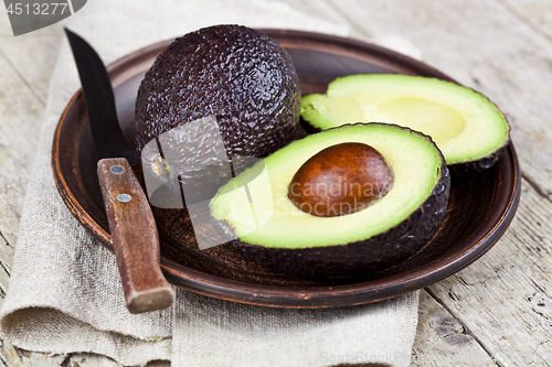 Image of Fresh organic avocado on ceramic plate and knife on  linen napki