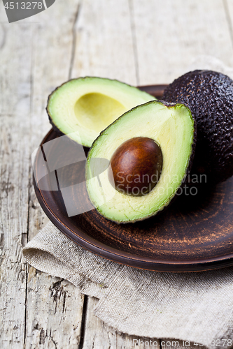 Image of Fresh organic avocado on ceramic plate and linen napkin on rusti